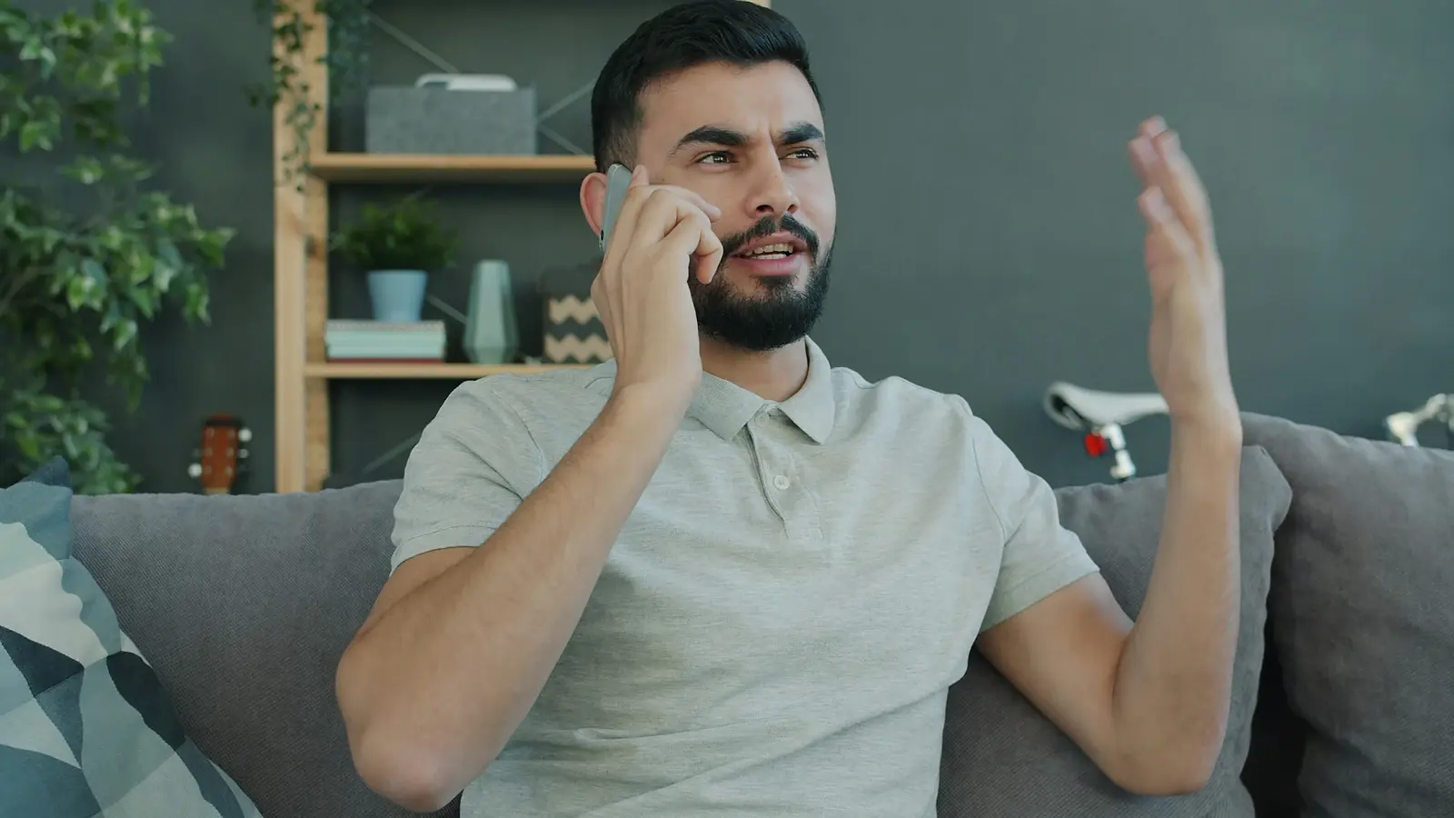 A man on his living room sofa, talking on the phone