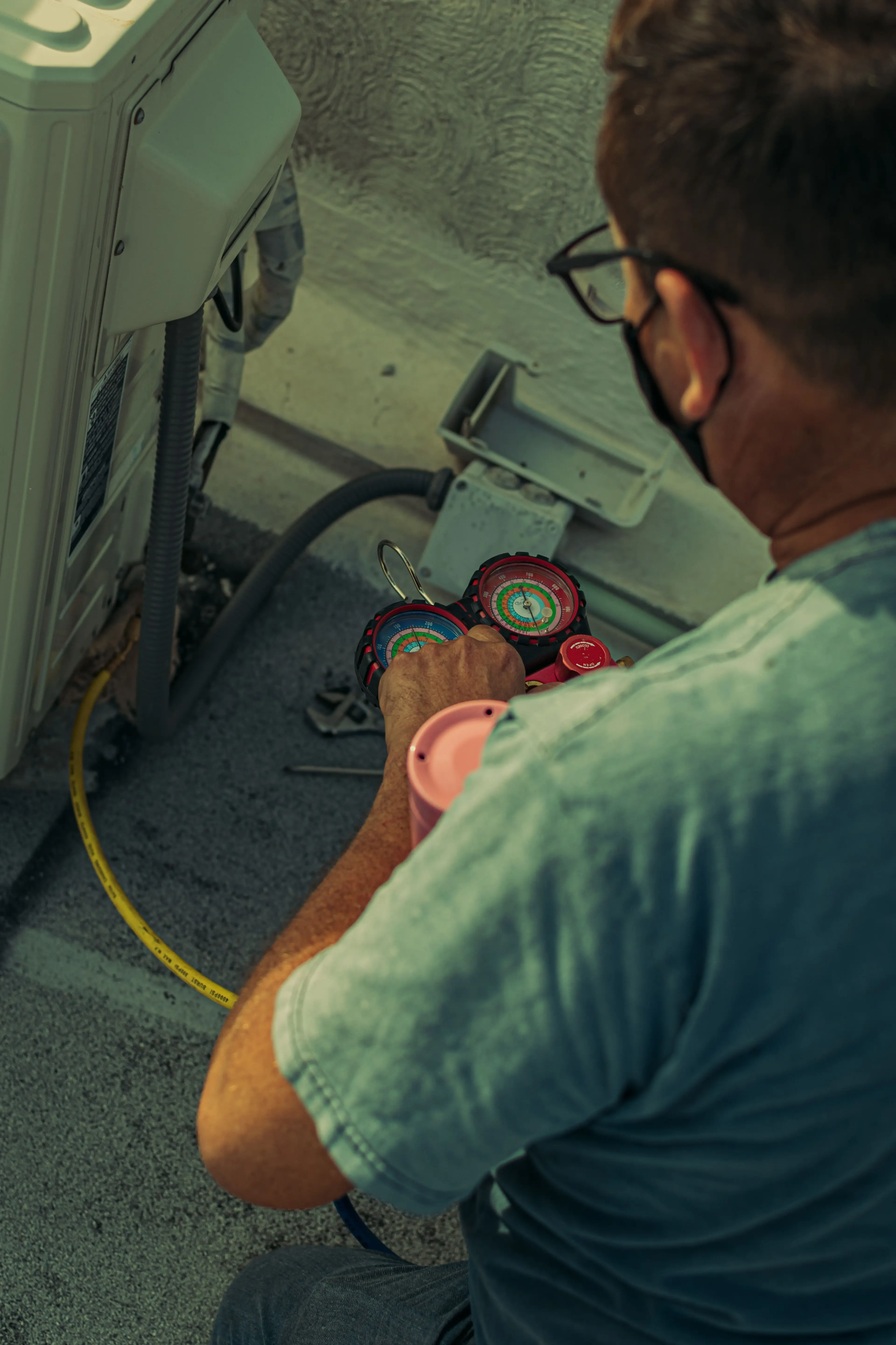 HVAC pro reading AC pressure gauges on a hot day that calls for AC repair in Olivehurst
