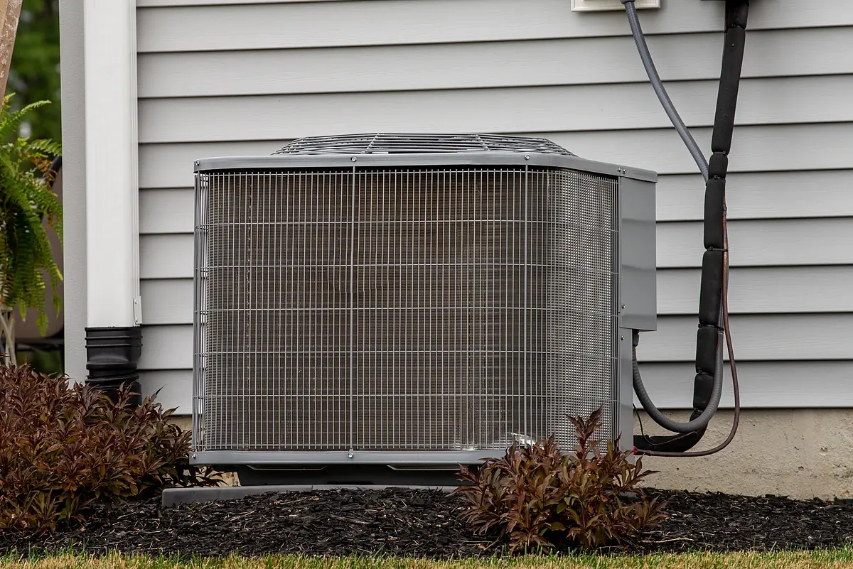 Older outdoor AC unit beside a house